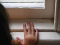 Photo of a child's hand on a window seal